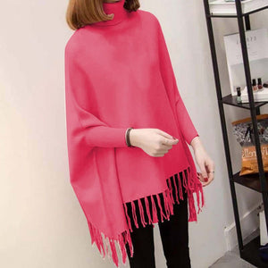 Person wearing a bright pink poncho with tassels indoors.