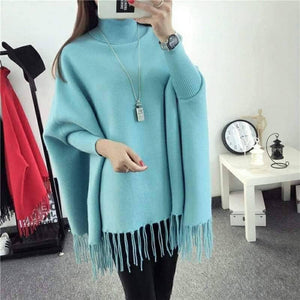 Light blue poncho with fringe details worn by a person, with a minimal background.