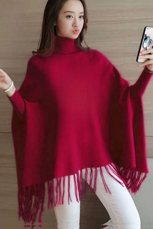 Woman wearing a red poncho with tassels, taking a selfie.